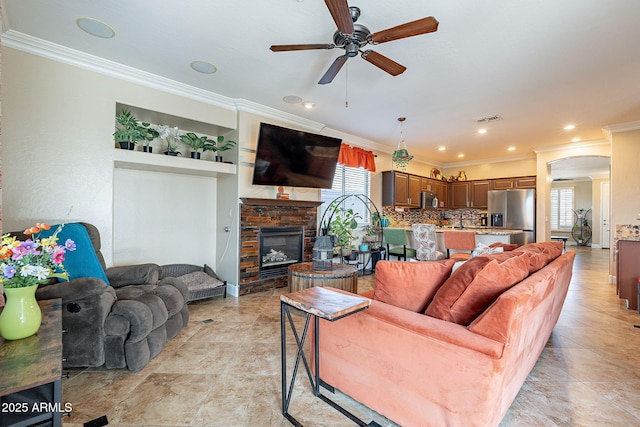 living room featuring a stone fireplace, ornamental molding, and ceiling fan