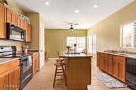 kitchen featuring light tile patterned floors, sink, a breakfast bar area, a center island, and black appliances