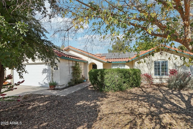 mediterranean / spanish house featuring a garage and solar panels