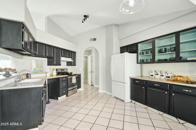 kitchen featuring sink, stainless steel electric range, light tile patterned floors, high vaulted ceiling, and white fridge