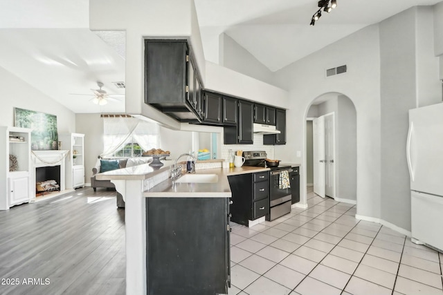 kitchen with stainless steel electric range oven, lofted ceiling, sink, white fridge, and kitchen peninsula