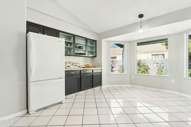 kitchen with light tile patterned flooring, decorative light fixtures, lofted ceiling, decorative backsplash, and white refrigerator