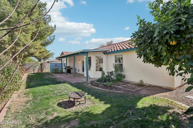 back of house with a yard, a fire pit, and a patio area