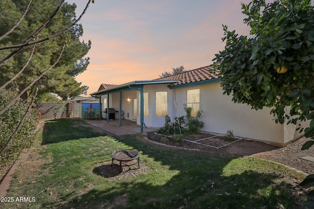 exterior space featuring a patio, a lawn, and an outdoor fire pit