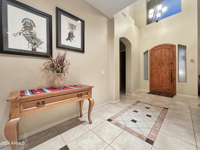 foyer entrance featuring a towering ceiling, light tile patterned floors, and a notable chandelier