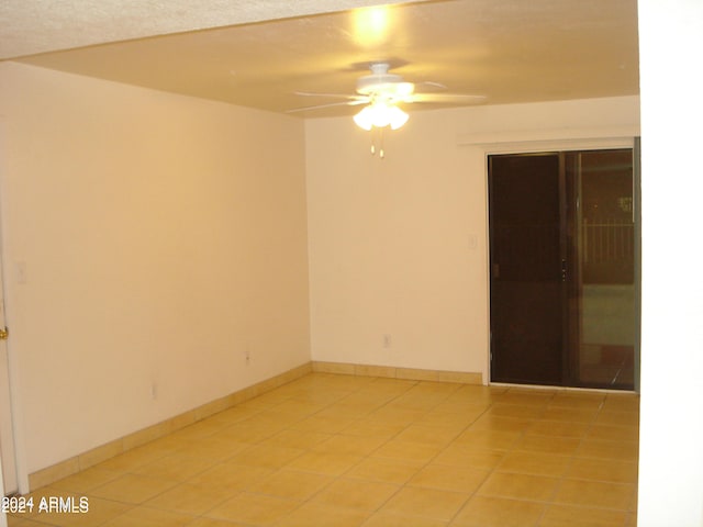 empty room with a textured ceiling, light tile patterned floors, and ceiling fan