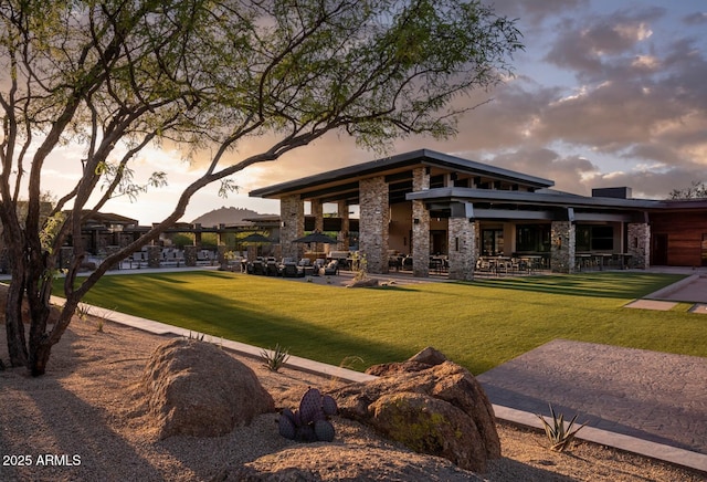 back house at dusk featuring a lawn