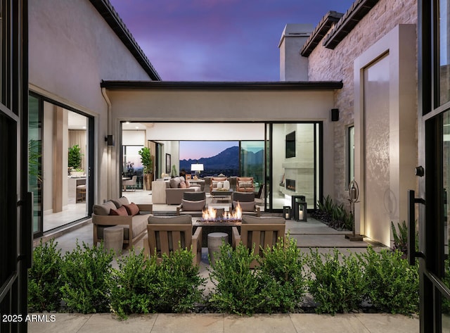 patio terrace at dusk featuring an outdoor living space with a fire pit