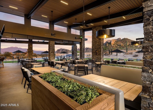 patio terrace at dusk featuring ceiling fan and a mountain view