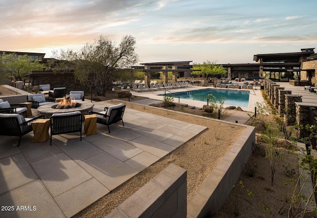 pool at dusk with a fire pit and a patio area