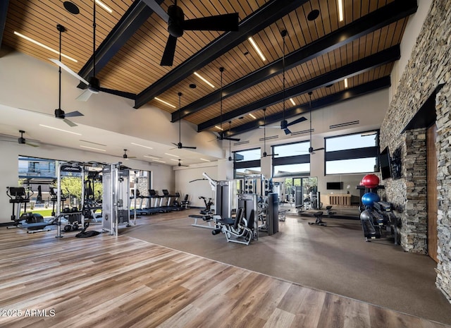 gym with hardwood / wood-style floors, ceiling fan, a towering ceiling, and wooden ceiling