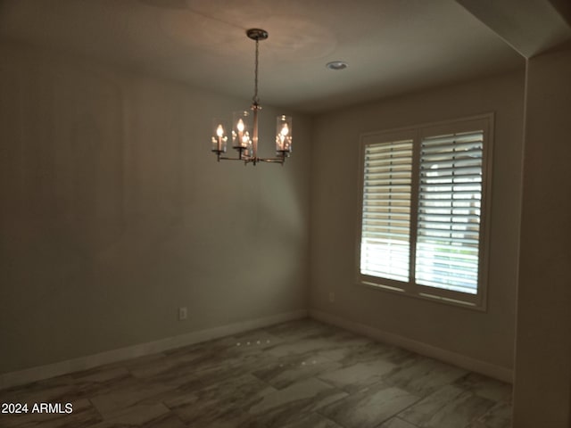 unfurnished room with a notable chandelier