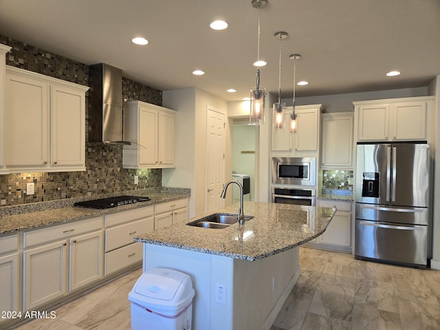 kitchen featuring a center island with sink, wall chimney exhaust hood, sink, pendant lighting, and appliances with stainless steel finishes