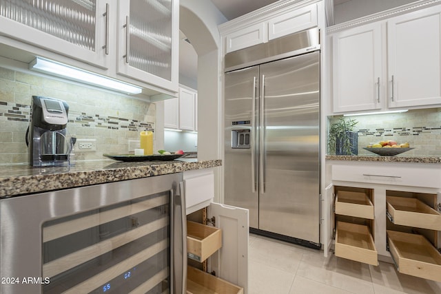 kitchen with wine cooler, light tile patterned flooring, white cabinetry, built in refrigerator, and backsplash