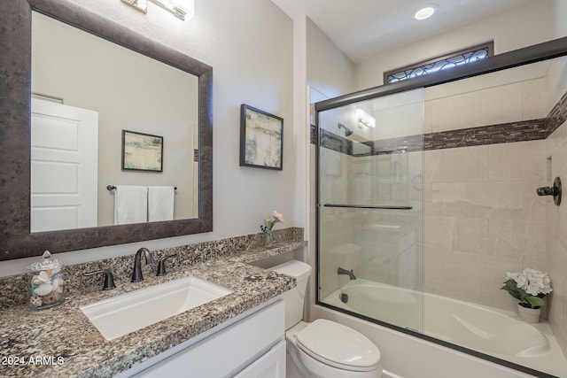 full bathroom with enclosed tub / shower combo, vanity, and toilet