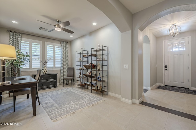 tiled entrance foyer featuring ceiling fan with notable chandelier