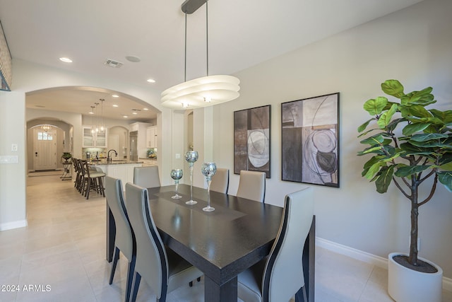 tiled dining room featuring an inviting chandelier and sink