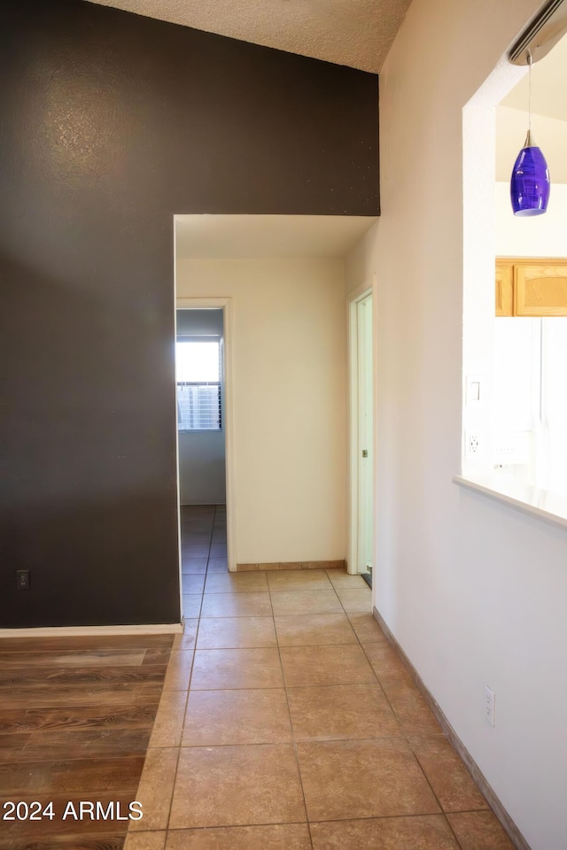 hall featuring tile patterned floors and lofted ceiling