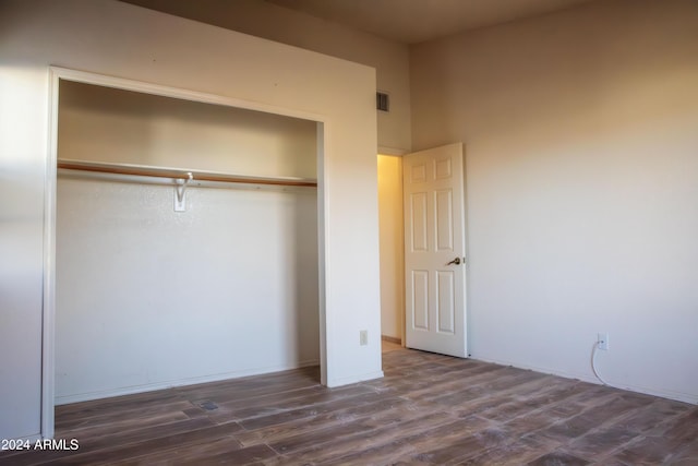 unfurnished bedroom with a closet and dark wood-type flooring