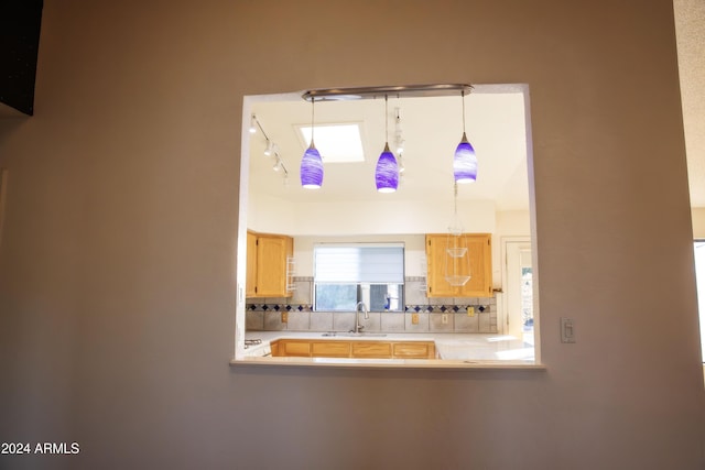 interior details with pendant lighting, backsplash, light brown cabinets, and sink