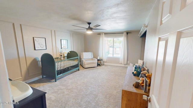 interior space with a decorative wall, a textured ceiling, baseboards, and ceiling fan