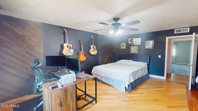 bedroom with ceiling fan, wood finished floors, visible vents, and baseboards