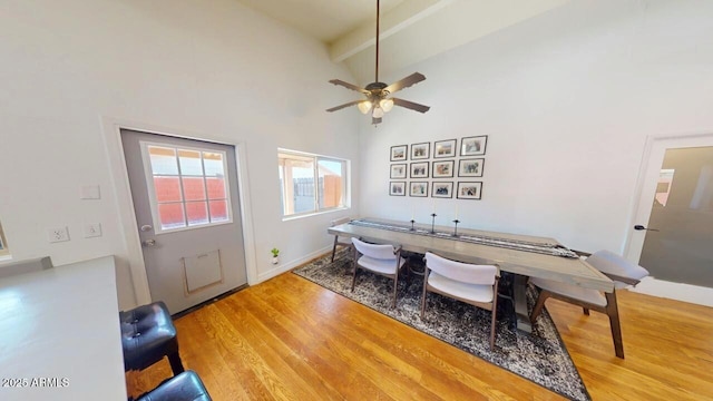 dining area featuring high vaulted ceiling, beamed ceiling, light wood-style flooring, and a ceiling fan