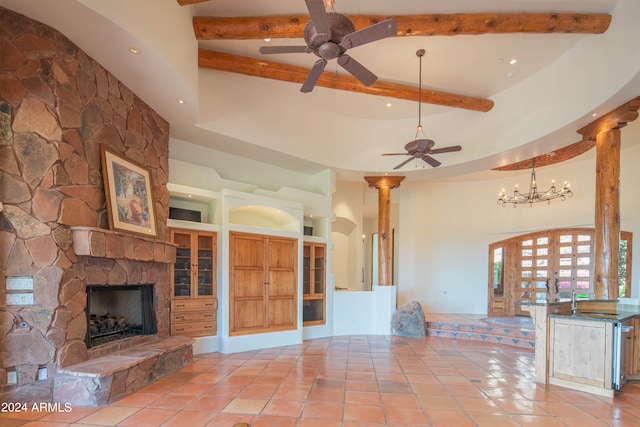 unfurnished living room featuring ceiling fan with notable chandelier, beam ceiling, built in shelves, a fireplace, and light tile floors