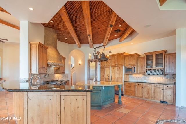 kitchen with a kitchen breakfast bar, beamed ceiling, backsplash, stainless steel microwave, and light tile floors