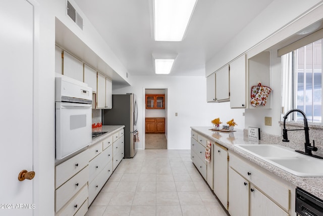 kitchen with white cabinets, appliances with stainless steel finishes, sink, and light tile patterned floors