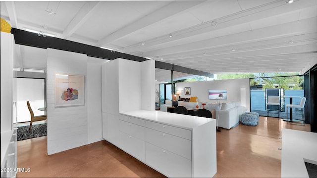 5714 N 11th St, Phoenix, AZ 85014 - kitchen featuring concrete floors, beamed ceiling, a peninsula, white cabinets, and open floor plan