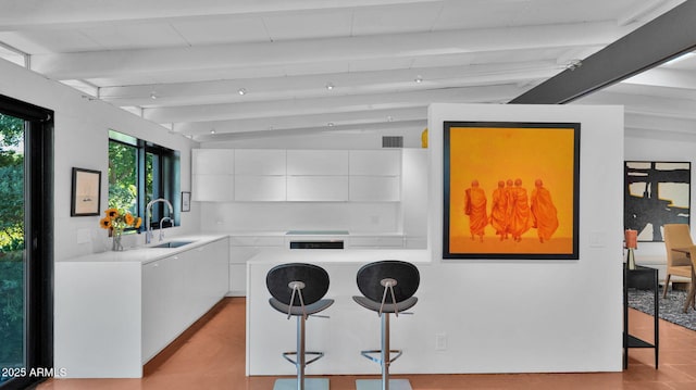 5714 N 11th St, Phoenix, AZ 85014 - kitchen featuring a sink, white cabinetry, a breakfast bar, beam ceiling, and light countertops