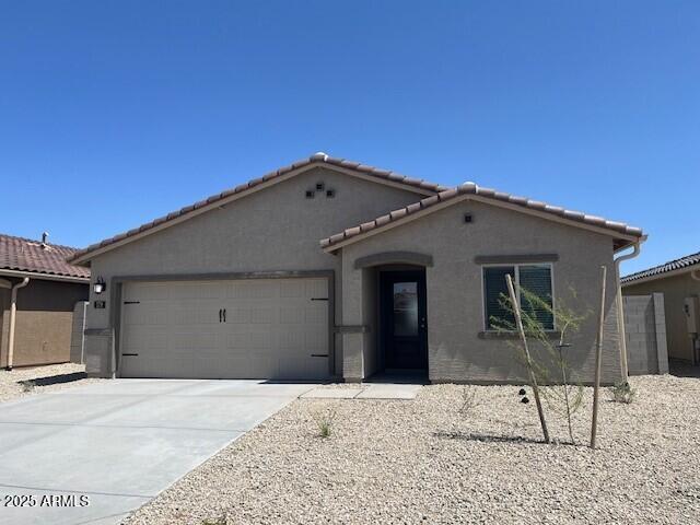 view of front of home with a garage, a tile roof, concrete driveway, and stucco siding