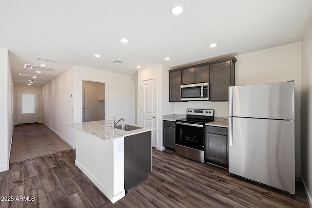 kitchen featuring stainless steel appliances, dark wood-style flooring, a sink, visible vents, and an island with sink