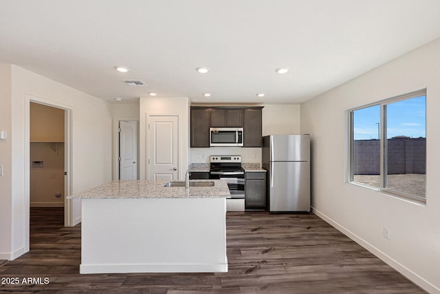 kitchen featuring dark wood-style floors, a center island with sink, stainless steel appliances, visible vents, and dark brown cabinetry