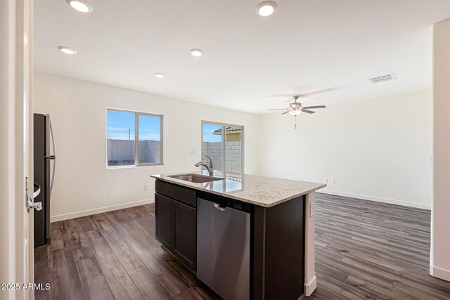 kitchen featuring dark wood-style floors, stainless steel appliances, a sink, and a center island with sink