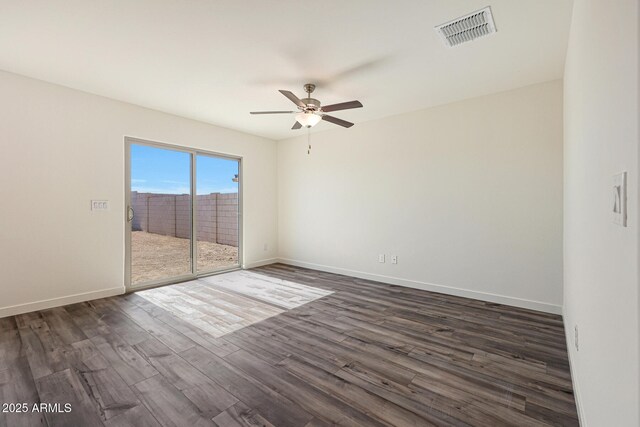 spare room with dark wood-style floors, baseboards, visible vents, and ceiling fan