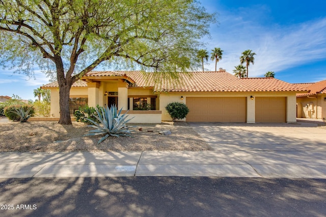 mediterranean / spanish home with a tiled roof, a garage, and stucco siding