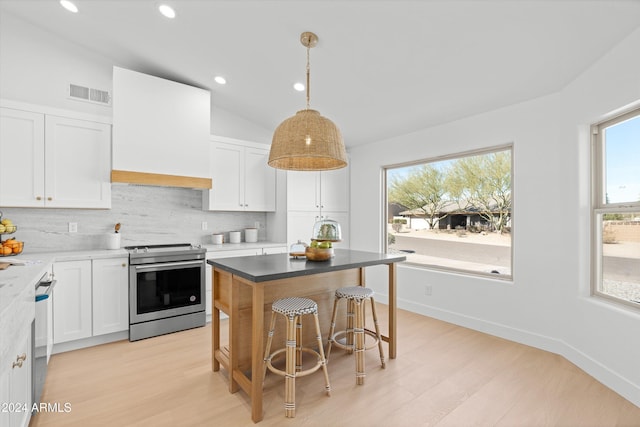 kitchen with appliances with stainless steel finishes, premium range hood, white cabinetry, and hanging light fixtures