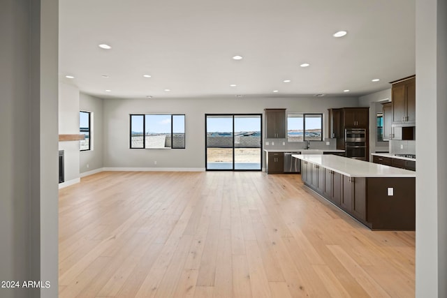 kitchen featuring a center island, light hardwood / wood-style flooring, stainless steel dishwasher, dark brown cabinets, and double oven