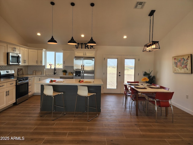 kitchen featuring pendant lighting, a center island, lofted ceiling, stainless steel appliances, and sink