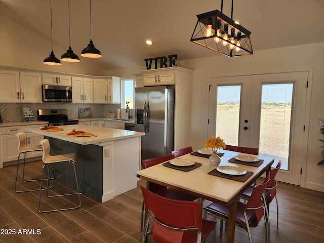 kitchen with pendant lighting, appliances with stainless steel finishes, a center island, white cabinetry, and french doors