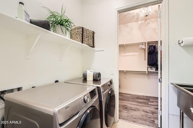 clothes washing area with washing machine and clothes dryer and light hardwood / wood-style flooring