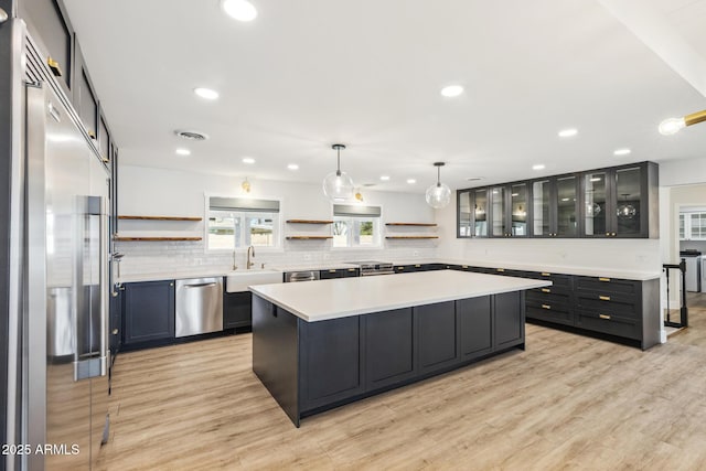 kitchen with tasteful backsplash, light wood-style flooring, a kitchen island, appliances with stainless steel finishes, and open shelves