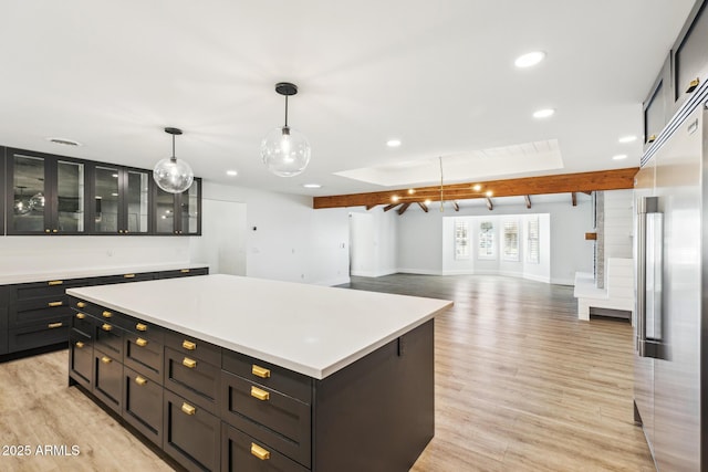 kitchen featuring built in refrigerator, light wood finished floors, a kitchen island, and light countertops