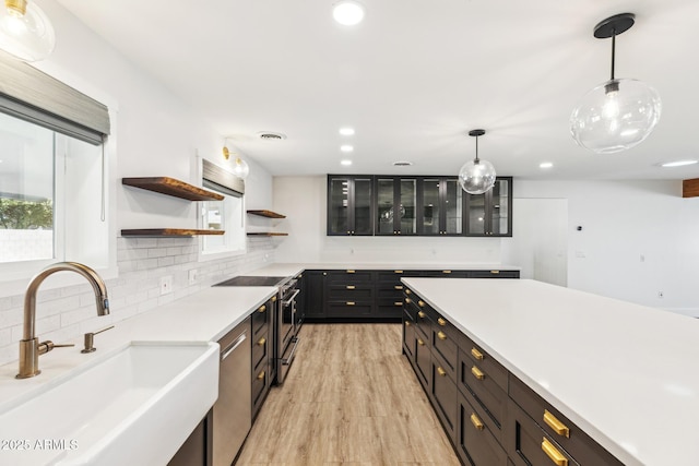 kitchen with open shelves, tasteful backsplash, appliances with stainless steel finishes, glass insert cabinets, and a sink