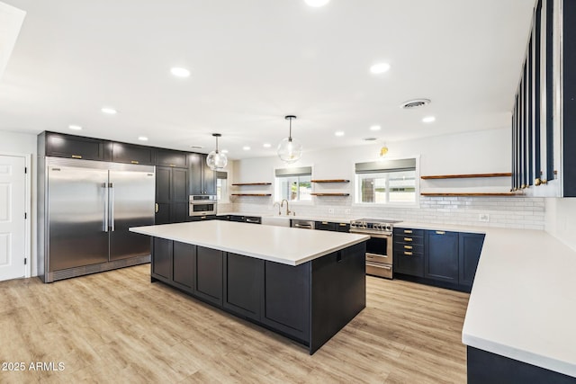 kitchen featuring visible vents, a kitchen island, appliances with stainless steel finishes, open shelves, and a sink