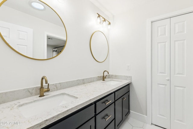 bathroom with baseboards, double vanity, a sink, and tile patterned floors