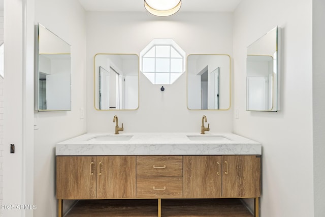 full bath featuring double vanity, wood finished floors, and a sink