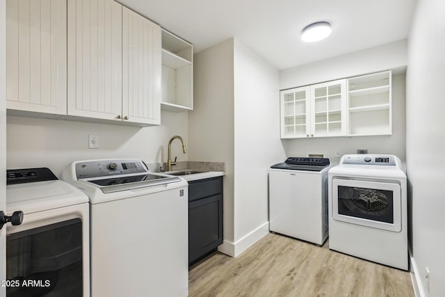 laundry room with separate washer and dryer, a sink, baseboards, light wood-type flooring, and cabinet space